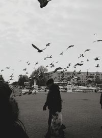 Full length of woman flying birds in city against sky