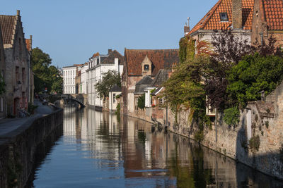 Arch bridge over river by buildings against sky in city