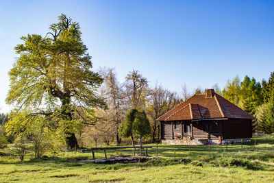 House on field by trees against sky