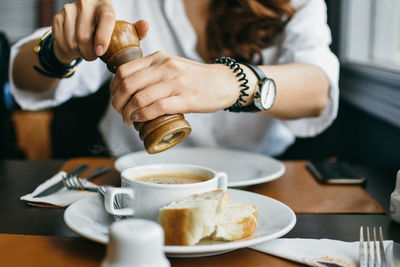 Midsection of woman seasoning coffee at cafe