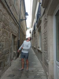 Rear view of man standing on alley amidst buildings