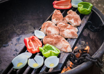 High angle view of meat with vegetables on barbecue grill