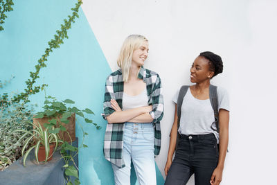 Smiling females standing against wall