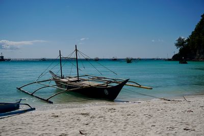 Fishing boat on beach against sky