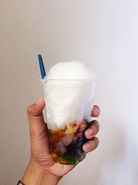 Hand holding ice cream cone against white background