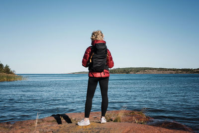 Rear view of woman standing on beach against clear sky