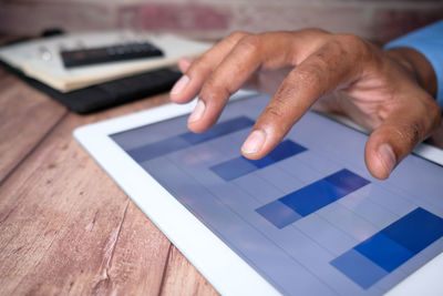 Midsection of man using smart phone on table