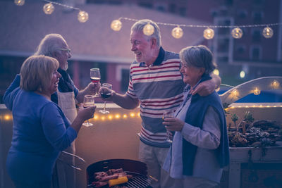 Happy friends toasting wines on building terrace during christmas