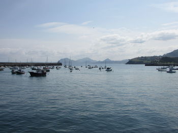 Sailboats moored in sea against sky