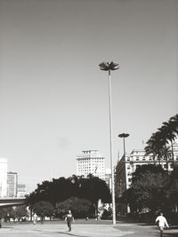 People walking on city street against clear sky