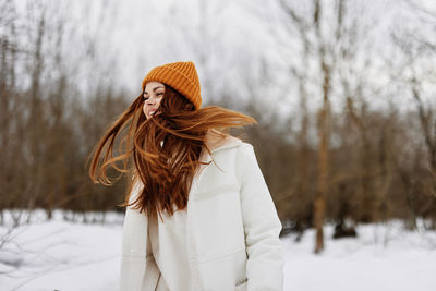 Portrait of young woman standing on snow covered field