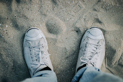 Low section of man standing on sand
