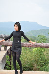 Young woman looking away while standing by railing on observation point against sky