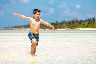 Full length of shirtless man standing on beach