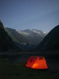 Tent on field against mountain range at night