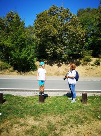 Mother with camera standing by son on grassy field