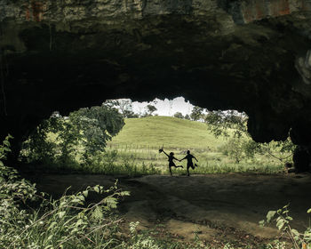 Silhouette of unidentified couple running inside a cave.