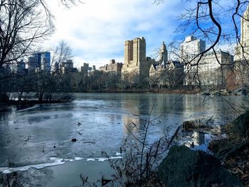 Scenic view of frozen lake by buildings against sky