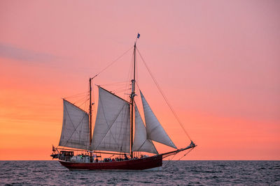 Sailboat sailing on sea against sky during sunset