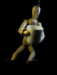 Water pouring in cup with figurine against black background