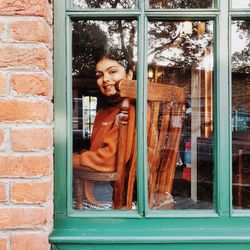 Portrait of smiling woman standing by window