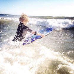 Side view of boy surfing at beach