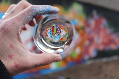 Close-up of cropped hand holding crystal ball by painting