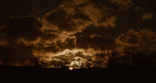 Low angle view of silhouette trees against dramatic sky