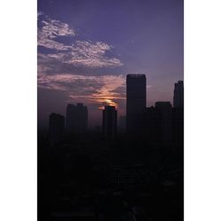 Skyscrapers in city at sunset