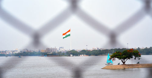 Flag on building by river against sky in city