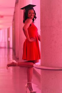 Portrait of woman standing against pink wall