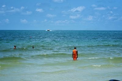 Monks in sea against sky