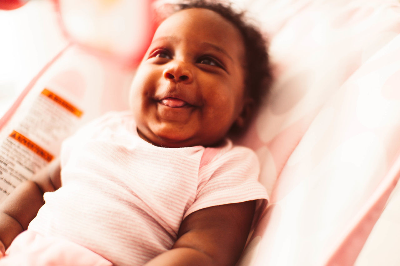 real people, child, portrait, one person, childhood, bed, furniture, lying down, front view, lifestyles, indoors, cute, lying on back, females, leisure activity, smiling, looking at camera, baby, innocence