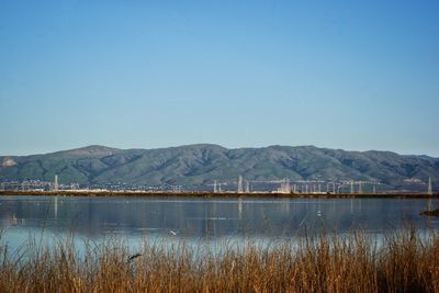 Scenic view of lake and mountains against clear blue sky