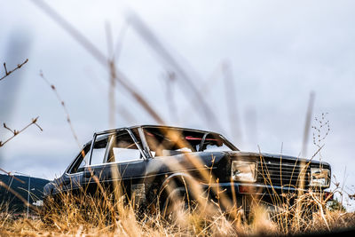 Abandoned car on field against sky