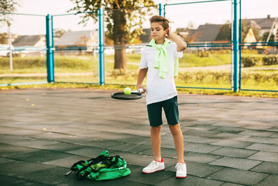 A young athlete is holding a tennis racket with a ball on it. tennis player warms up