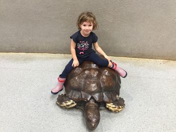 Portrait of smiling girl sitting on sculpture