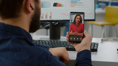 Midsection of man talking on video call at office