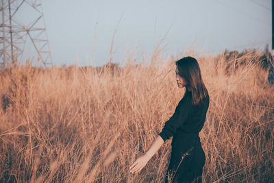 Side view of woman standing on field against sky