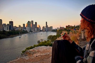 People photographing city against sky during sunset