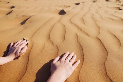 Midsection of person relaxing on sand at beach