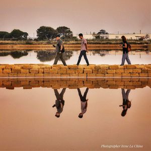 People standing by lake against clear sky