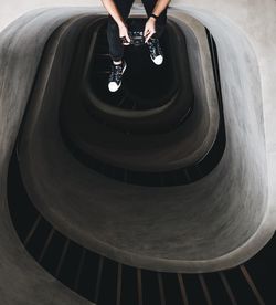 Low section of man sitting against spiral staircase in building