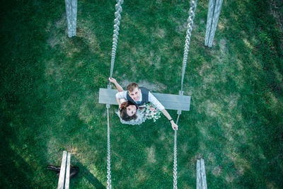 Bride and groom on swing at park
