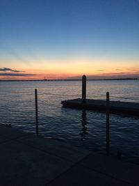 Silhouette wooden post in sea against sky during sunset