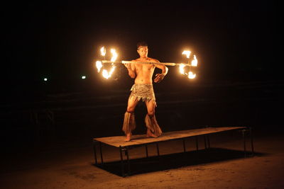 Full length of fire dancer on beach at night