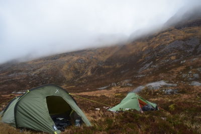 Tents on landscape against clouds