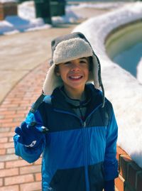 High angle portrait of happy boy in warm clothing standing at sidewalk