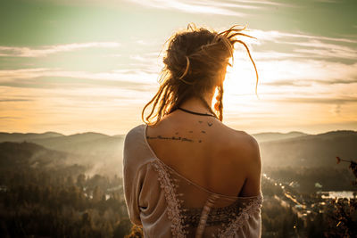 Rear view of woman looking at mountain during sunset