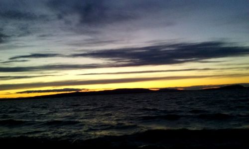 Scenic view of sea against cloudy sky at sunset